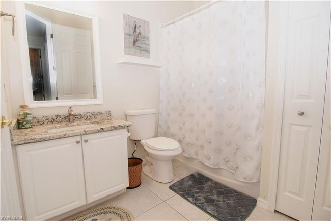 Second bathroom features a granite vanity and tub with shower. | Image 15
