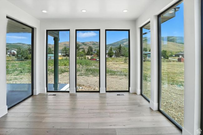 Unfurnished sunroom featuring a mountain view, wood-type flooring, and recessed lighting | Image 8