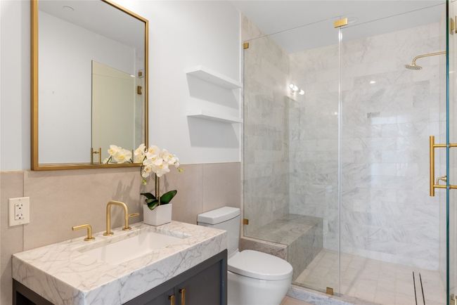 Bathroom featuring toilet, a stall shower, vanity, and tile walls | Image 10