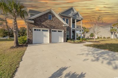 View of front of home with a garage, a balcony, and a yard | Image 1