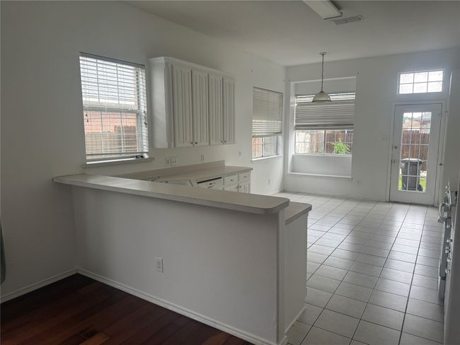 Kitchen with a peninsula, light countertops, visible vents, and white cabinetry | Image 7