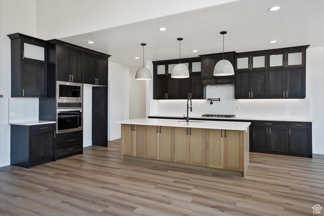 Kitchen with appliances with stainless steel finishes, a sink, light wood finished floors, and recessed lighting | Image 7