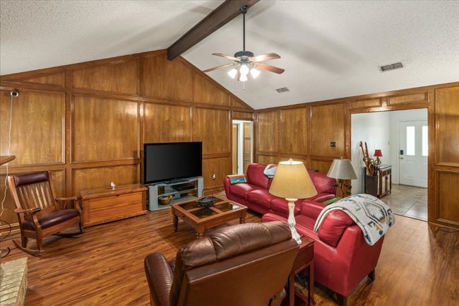 Living room with hardwood / wood-style flooring, a ceiling fan, wooden walls, and a textured ceiling | Image 6