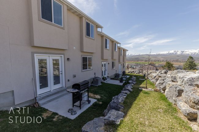 Back of property with entry steps, a mountain view, a lawn, and stucco siding | Image 27