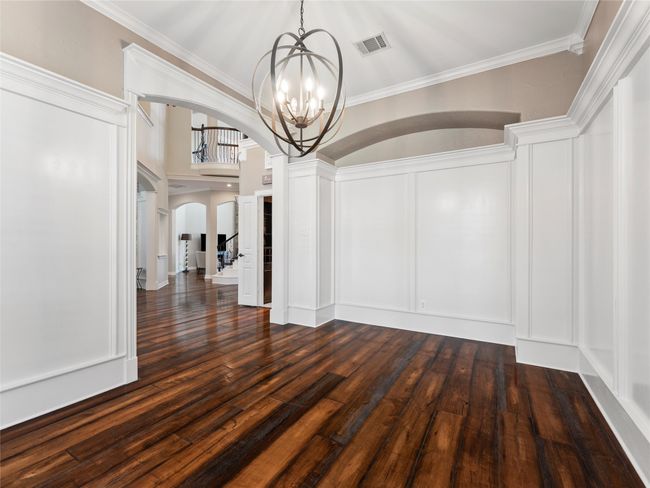Unfurnished dining area with arched walkways, a chandelier, dark wood-type flooring, and crown molding | Image 12