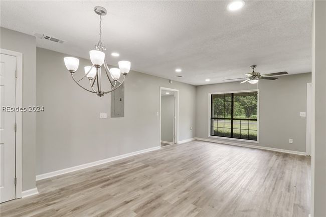 Unfurnished room featuring a textured ceiling, ceiling fan with notable chandelier, light hardwood / wood-style floors, and electric panel | Image 17
