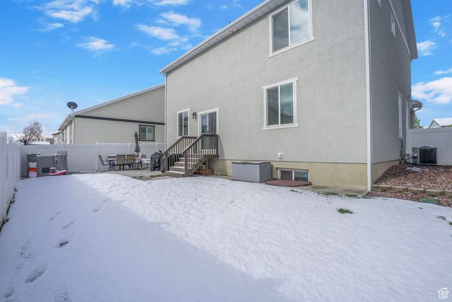 Snow covered rear of property with a patio area, a fenced backyard, central air condition unit, and stucco siding | Image 38