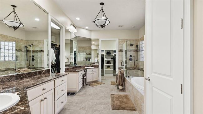 Exquisite primary bath with marble counter tops and an oversized frameless glass shower. Unwind in your jetted whirlpool tub to relax at the end of a long day. | Image 33