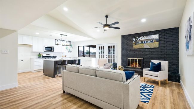 Living area with baseboards, ceiling fan, light wood-style floors, a fireplace, and lofted ceiling | Image 4