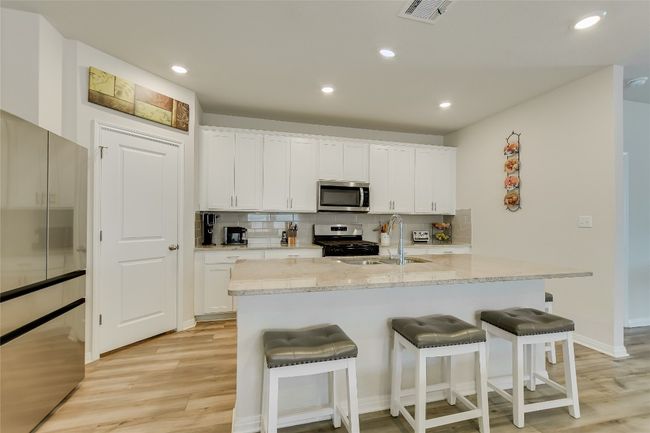 Kitchen featuring stainless steel appliances, a sink, light wood-style floors, a kitchen bar, and recessed lighting | Image 7