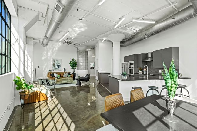 Kitchen featuring stainless steel appliances, wall chimney range hood, dark countertops, finished concrete flooring, and gray cabinetry | Image 7