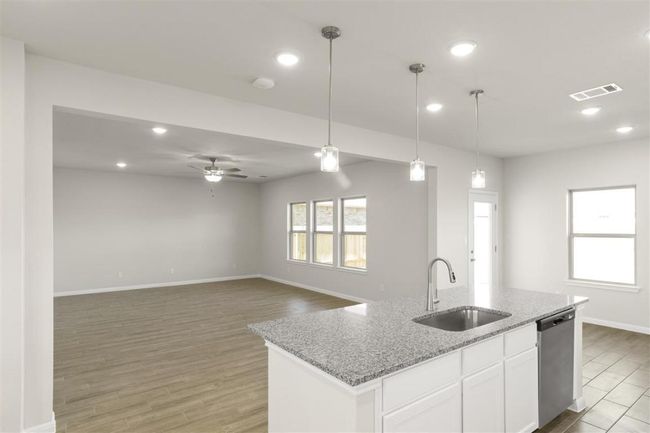Kitchen with light wood-type flooring, dishwasher, a ceiling fan, pendant lighting, and a sink | Image 13