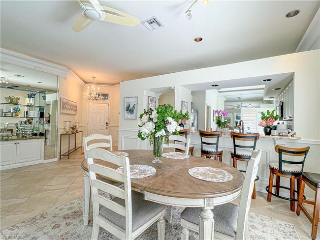 Dining space featuring crown molding, light tile floors, and ceiling fan with notable chandelier | Image 33