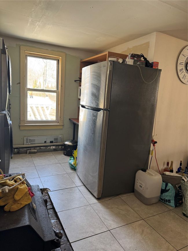 Kitchen featuring light tile patterned flooring, stacked washer / dryer, and freestanding refrigerator | Image 11