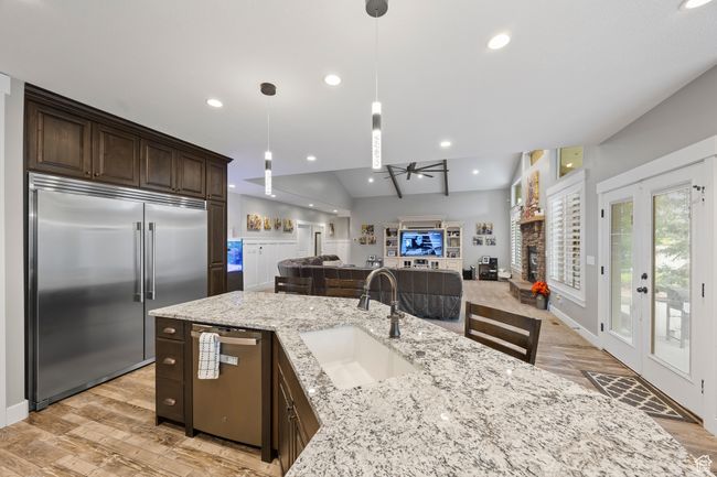 Kitchen with appliances with stainless steel finishes, a sink, dark brown cabinetry, a ceiling fan, and light wood-type flooring | Image 12