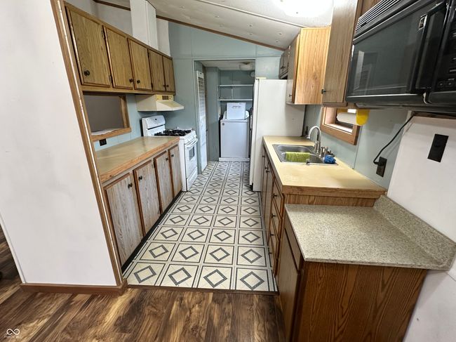 kitchen featuring lofted ceiling, white appliances, washer / clothes dryer, a sink, and extractor fan | Image 27