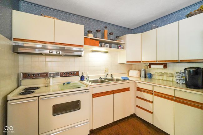 kitchen featuring double oven range, wall chimney range hood, light countertops, backsplash, and a sink | Image 17