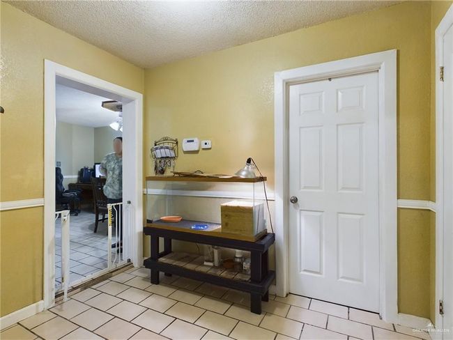 Hallway featuring light tile floors and a textured ceiling | Image 14