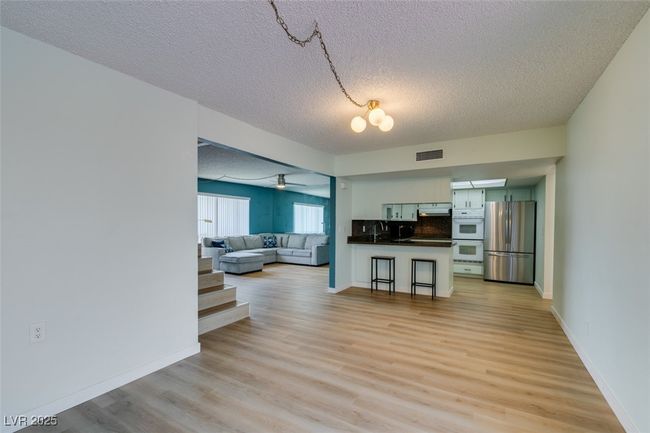 Living room with a textured ceiling, light wood finished floors, and ceiling fan | Image 18