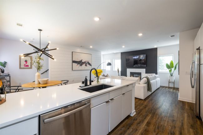 Kitchen with a sink, light countertops, dark wood finished floors, a fireplace, and stainless steel appliances | Image 10