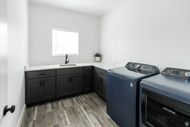 Laundry area with light wood-style floors, washer and clothes dryer, cabinet space, and a sink | Image 19