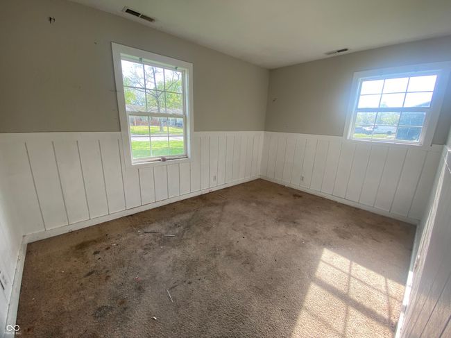 empty room with a wainscoted wall, visible vents, and a healthy amount of sunlight | Image 14