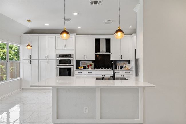 Kitchen with wall chimney and breakfast bar island. | Image 13