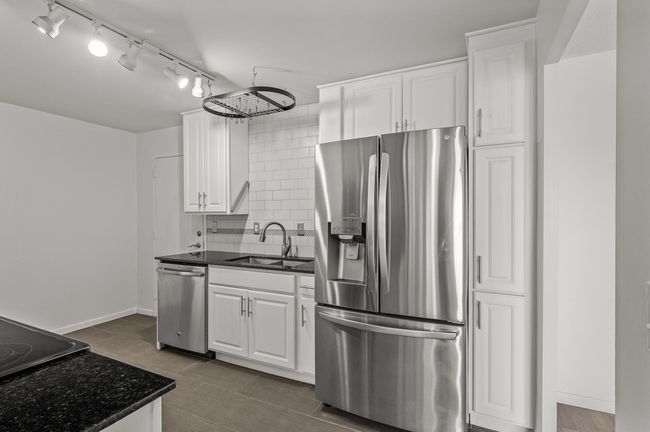 Newer kitchen with white cabinets, granite counters, ceramic tile backsplash & floors and stainless steel appliances | Image 9