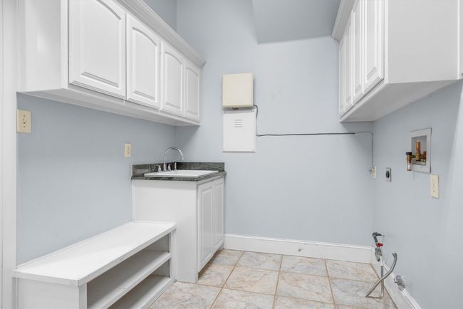Well-equipped laundry room featuring a sink, shelving, and built-in cabinets, offering plenty of storage and organization for everyday essentials. | Image 19