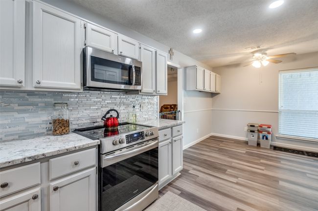 Kitchen featuring stainless steel appliances, a ceiling fan, tasteful backsplash, a textured ceiling, and light wood-type flooring | Image 9