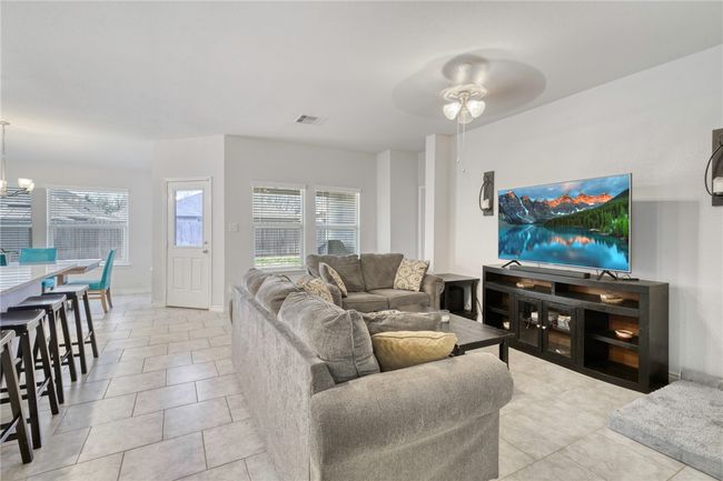 Tiled living room featuring ceiling fan with notable chandelier | Image 9