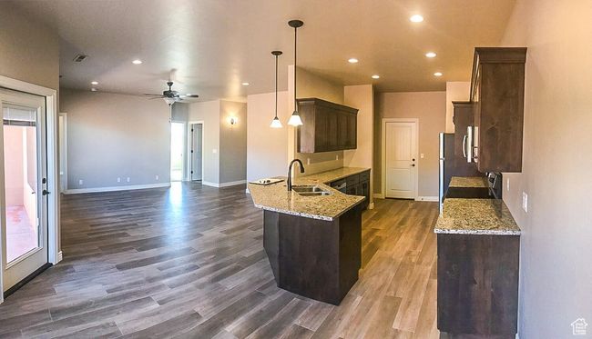 Kitchen with dark wood-style floors, a sink, light stone countertops, baseboards, and dark brown cabinetry | Image 22