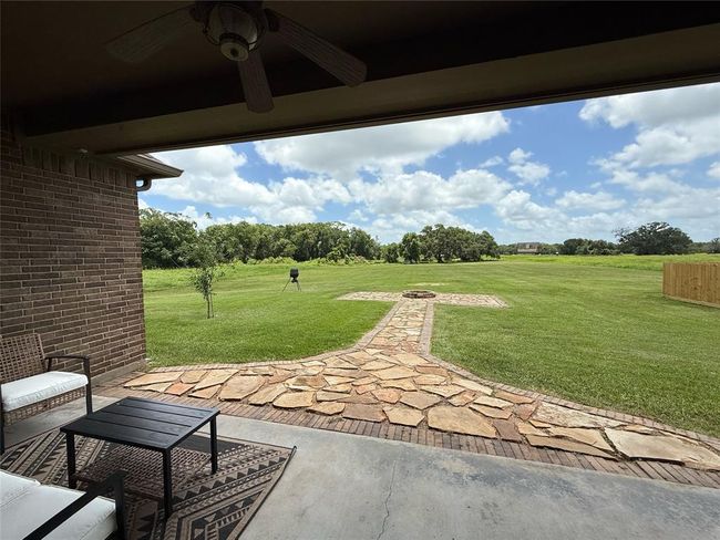 Covered back porch leading to firepit with view of Mills Bayou and large, beautiful oak trees | Image 19