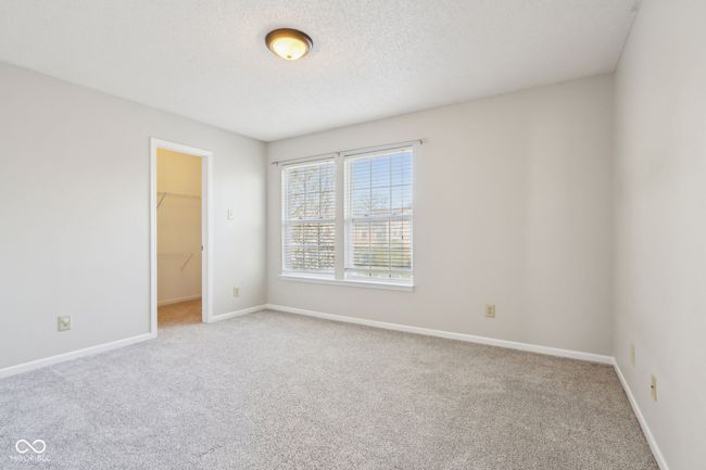 unfurnished bedroom with light colored carpet, a spacious closet, baseboards, and a closet | Image 54