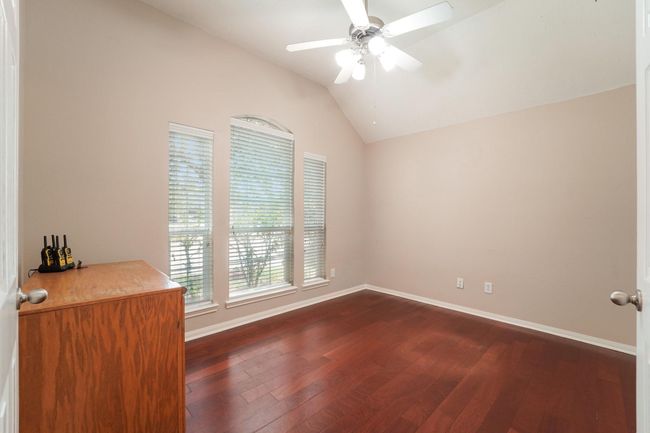 This study features hardwood flooring and neutral walls, with ample natural light from three large windows. This room is perfect for a home-office. | Image 9