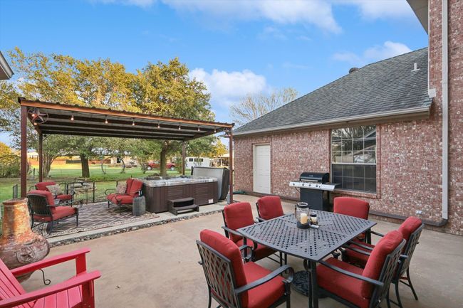 View of patio featuring a hot tub, grilling area, and outdoor dining space | Image 6