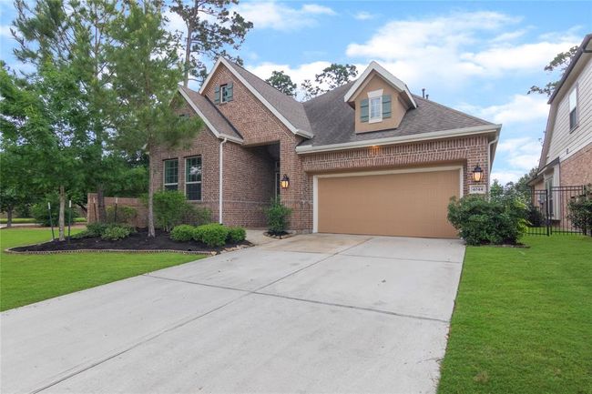 Charming brick home with well-maintained landscaping. Features a dormer window above the garage. The lush landscape has a welcoming curb appeal. The spacious driveway adds convenience. | Image 4