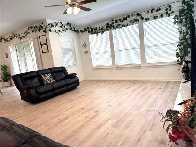 Living area featuring wood finished floors, ceiling fan, baseboards, and lofted ceiling | Image 6