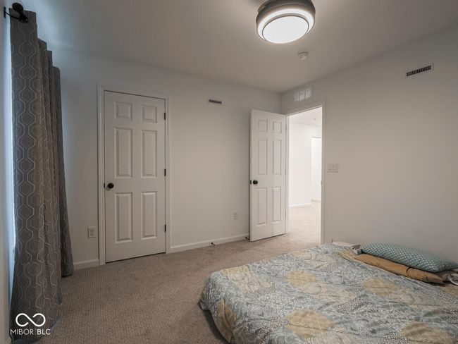 carpeted bedroom featuring baseboards and visible vents | Image 43