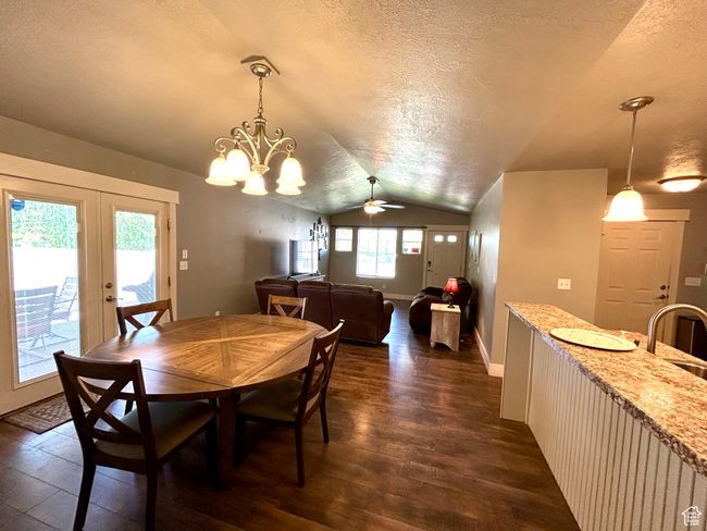 Dining area featuring vaulted ceiling, a textured ceiling, dark wood finished floors, french doors, and a ceiling fan | Image 20
