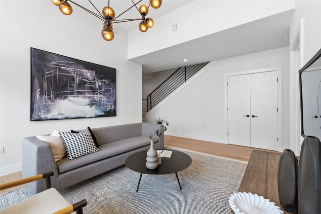 Living area featuring wood finished floors, stairs, baseboards, a towering ceiling, and a chandelier | Image 24