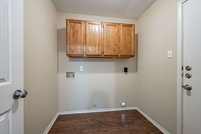 Clothes washing area featuring hookup for a washing machine, cabinet space, dark wood-style flooring, and baseboards | Image 28