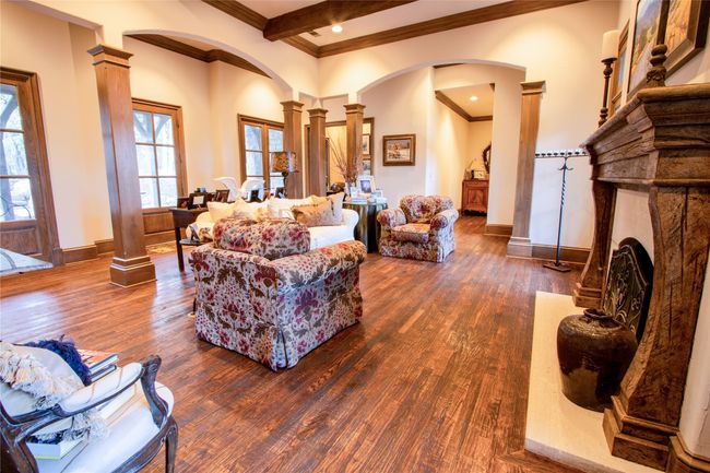 Living area with decorative columns, arched walkways, a fireplace with raised hearth, and dark wood-style flooring | Image 9