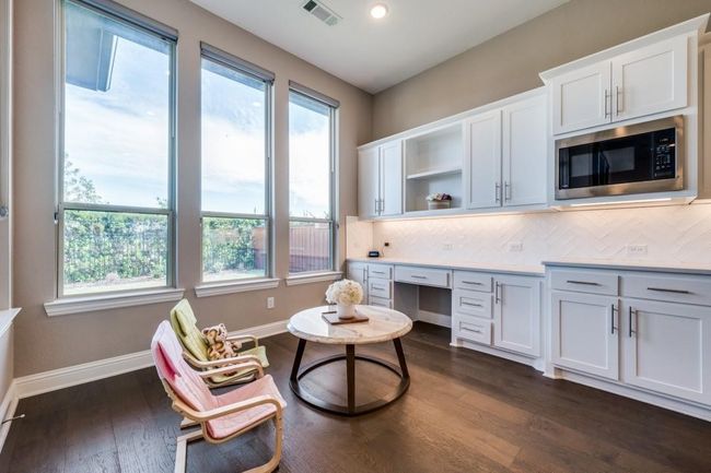 Office area featuring dark wood-style flooring, baseboards, and built in desk | Image 20