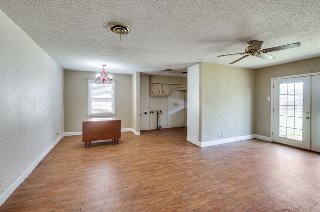Unfurnished room with ceiling fan with notable chandelier, a textured ceiling, light hardwood / wood-style floors, and french doors | Image 10
