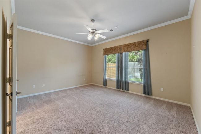 The primary bedroom features soft carpet flooring and elegant crown molding, offering a comfortable and stylish retreat within the home, along with a ceiling fan for ultimate comfort. | Image 31