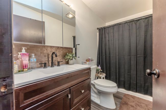 Full bathroom featuring tasteful backsplash, a shower with shower curtain, toilet, vanity, and wood finished floors | Image 17