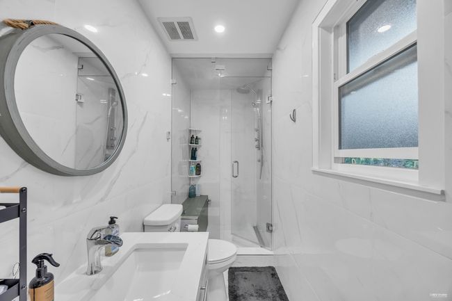 Full bath featuring a marble finish shower, healthy amount of natural light, and vanity | Image 22