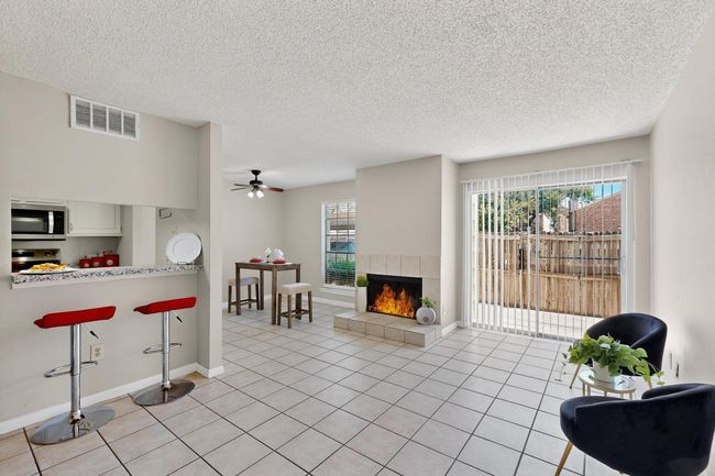 Living area featuring a textured ceiling, a fireplace, ceiling fan, and light tile patterned floors | Image 9