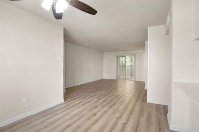 Empty room featuring light hardwood / wood-style flooring, ceiling fan, and a textured ceiling | Image 2